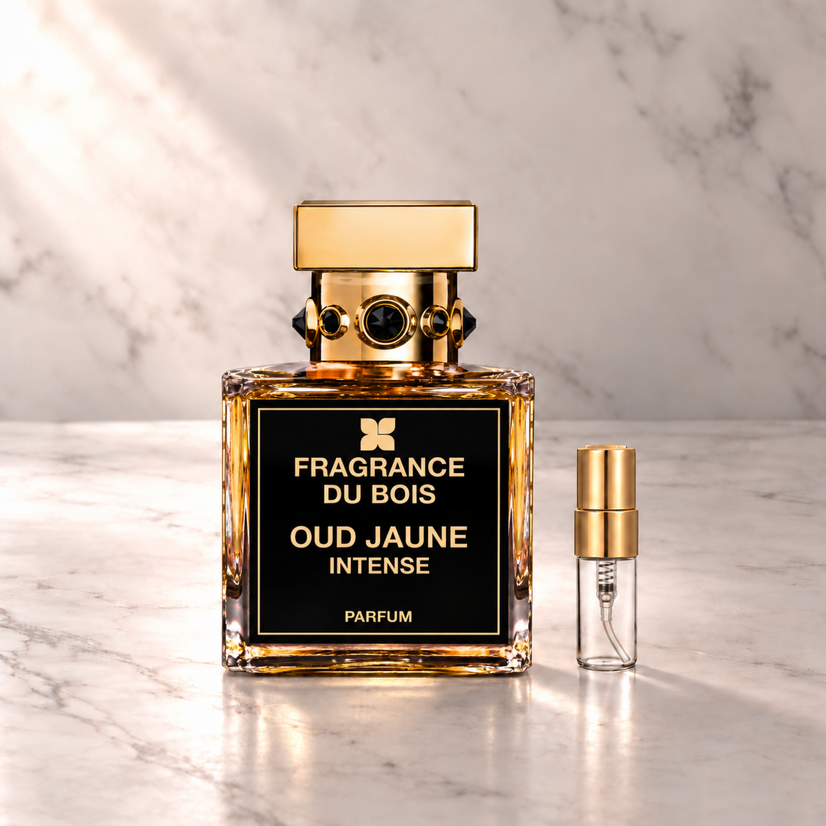 Fragrance du Bois Oud Jaune Intense Parfum mit 3-ml-Duftprobe aus Glas mit Goldkappe auf hellem Marmor