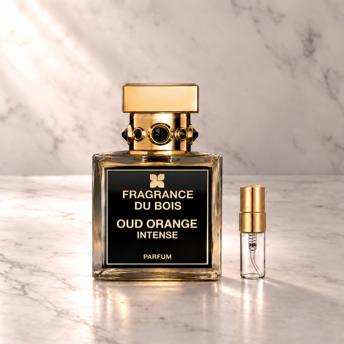 Fragrance du Bois Oud Orange Intense Parfum mit 3-ml-Duftprobe aus Glas mit Goldkappe auf hellem Marmor