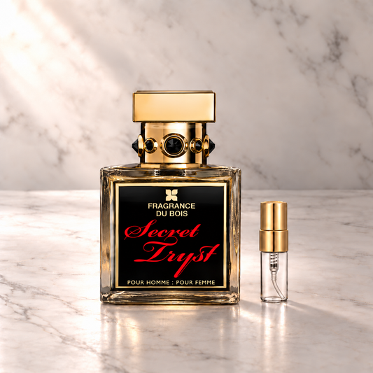 Fragrance du Bois Secret Tryst Parfum mit 3-ml-Duftprobe aus Glas mit Goldkappe auf hellem Marmor