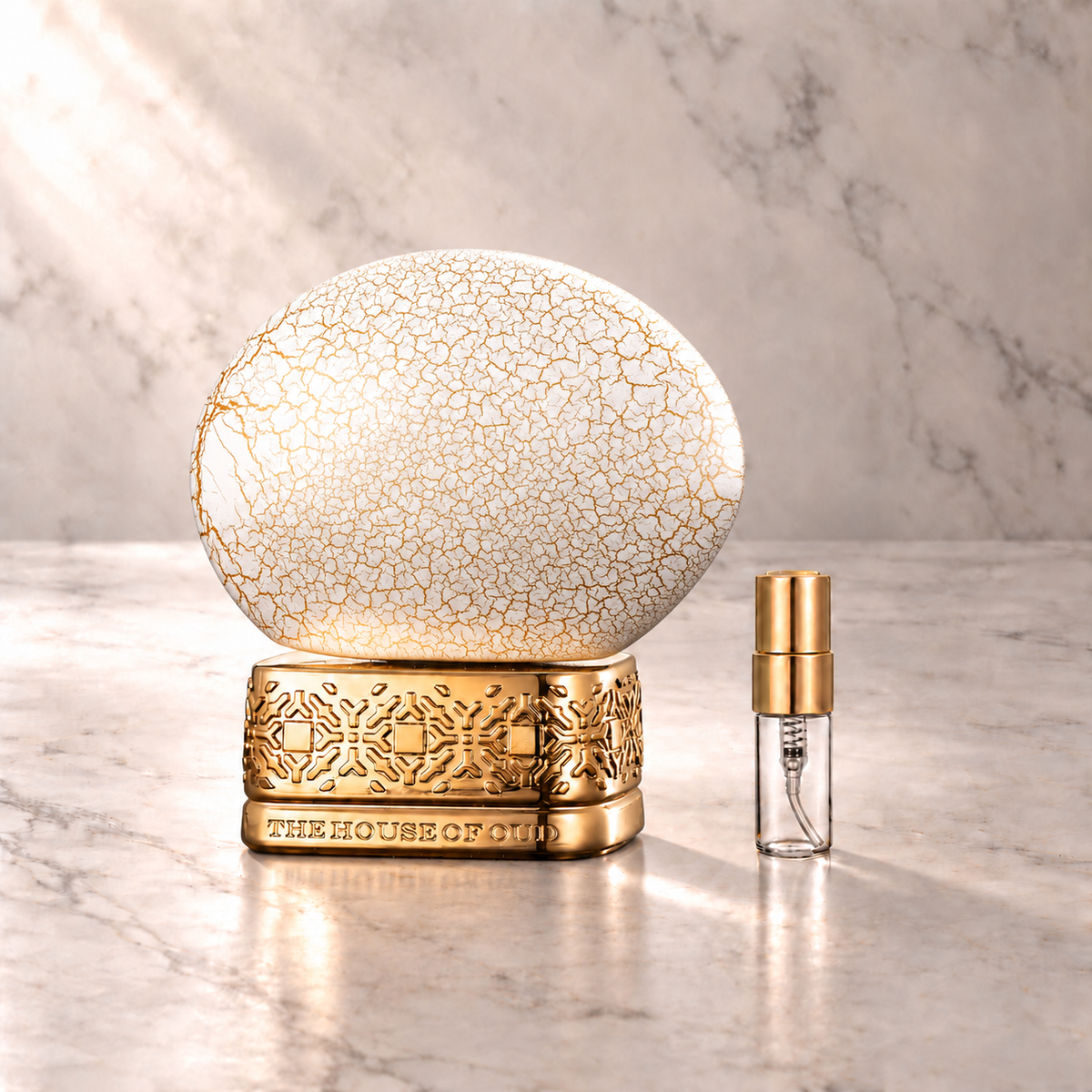 The House of Oud Breath of the Infinite Eau de Parfum mit 3-ml-Duftprobe aus Glas mit Goldkappe auf hellem Marmor