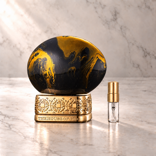 The House of Oud Dates Delight Eau de Parfum mit 3-ml-Duftprobe aus Glas mit Goldkappe auf hellem Marmor