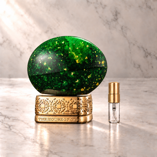 The House of Oud Emerald Green Eau de Parfum mit 3-ml-Duftprobe aus Glas mit Goldkappe auf hellem Marmor