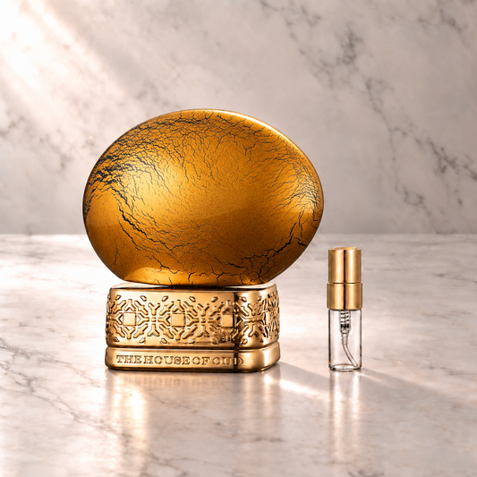 The House of Oud Golden Powder Eau de Parfum mit 3-ml-Duftprobe aus Glas mit Goldkappe auf hellem Marmor