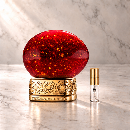 The House of Oud Ruby Red Eau de Parfum mit 3-ml-Duftprobe aus Glas mit Goldkappe auf hellem Marmor