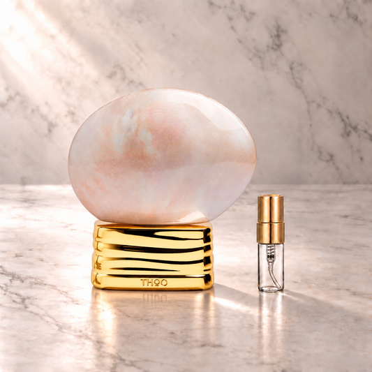 The House of Oud White Pearl Eau de Parfum mit 3-ml-Duftprobe aus Glas mit Goldkappe auf hellem Marmor